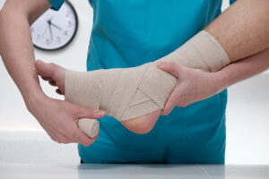 Female doctor wrapping up the injured ankle of a male patient